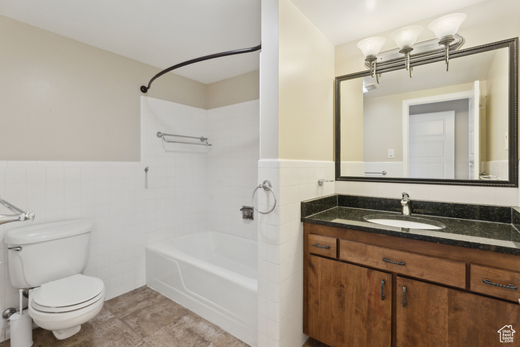 Full bath with tile walls, shower / tub combination, toilet, wainscoting, and vanity