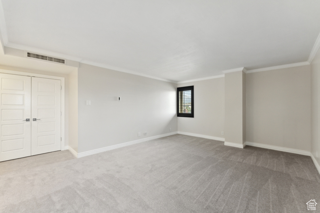 Carpeted empty room with crown molding and baseboards