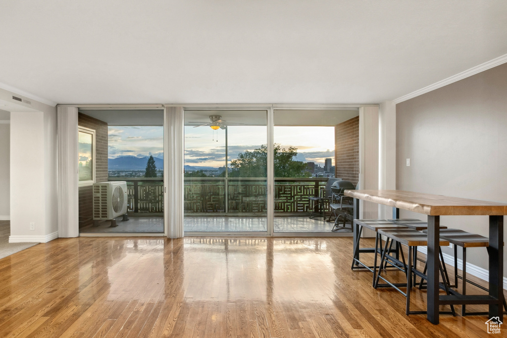 Dining space with floor to ceiling windows, wood finished floors, a ceiling fan, crown molding, and baseboards