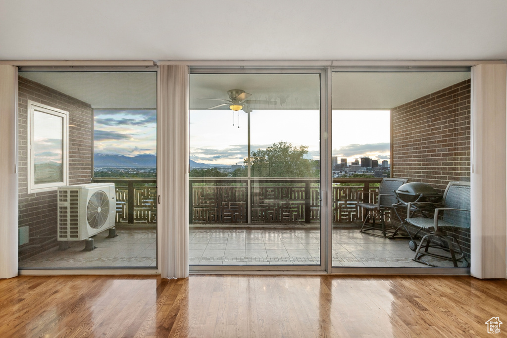Doorway featuring expansive windows, wood finished floors, ac unit, and ceiling fan