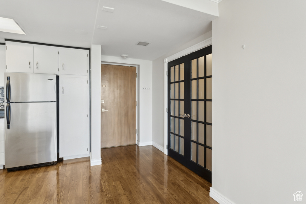 Kitchen featuring freestanding refrigerator, wood finished floors, white cabinets, and baseboards