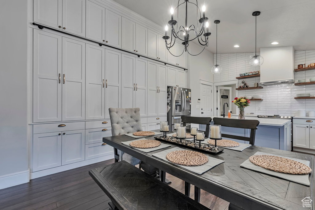 Dining area featuring a chandelier, dark wood finished floors, recessed lighting, and a high ceiling