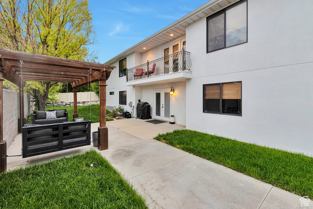 Back of house featuring french doors, a balcony, stucco siding, a pergola, and a patio area