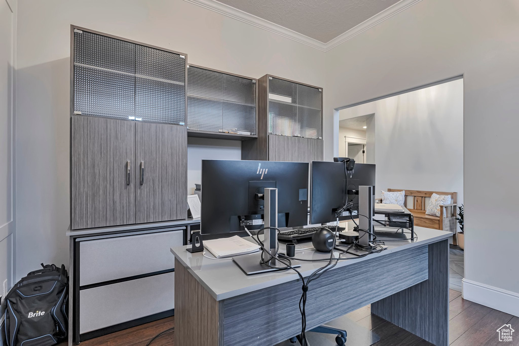 Office space with ornamental molding, dark wood-type flooring, and baseboards