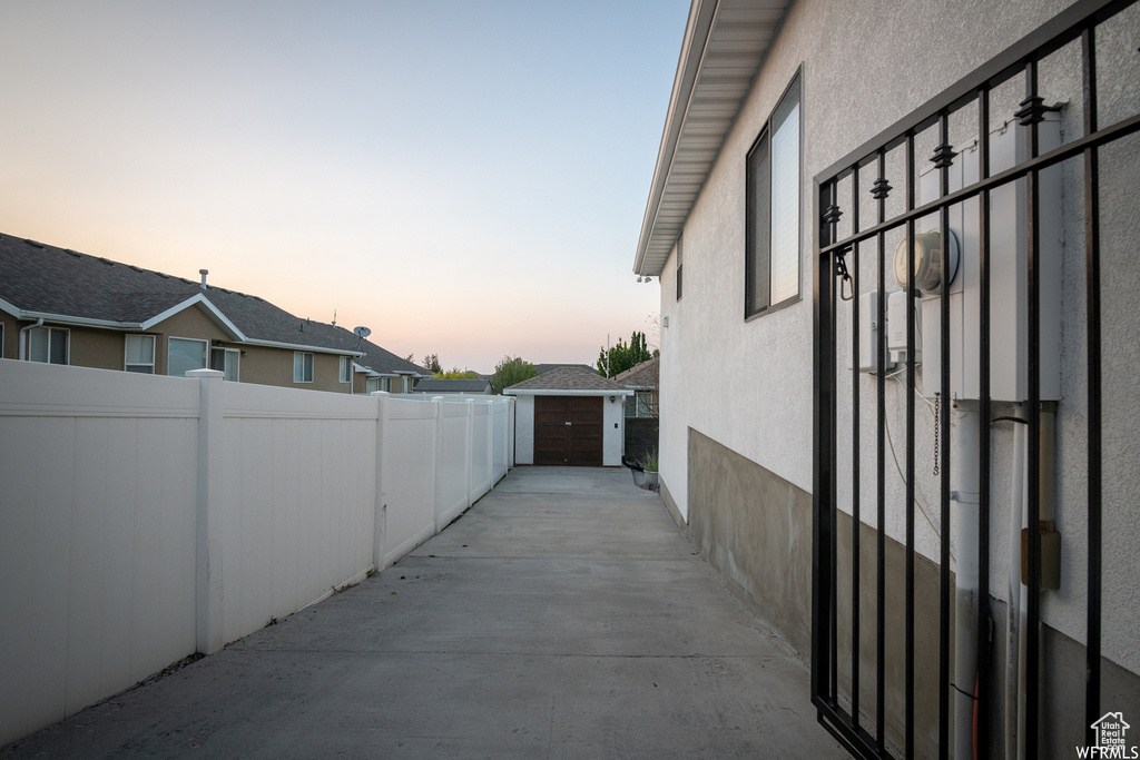 View of side of home with stucco siding, fence, and an outbuilding