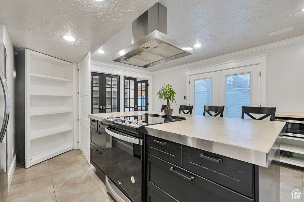 Kitchen featuring french doors, island exhaust hood, range with electric stovetop, a textured ceiling, and dark cabinets