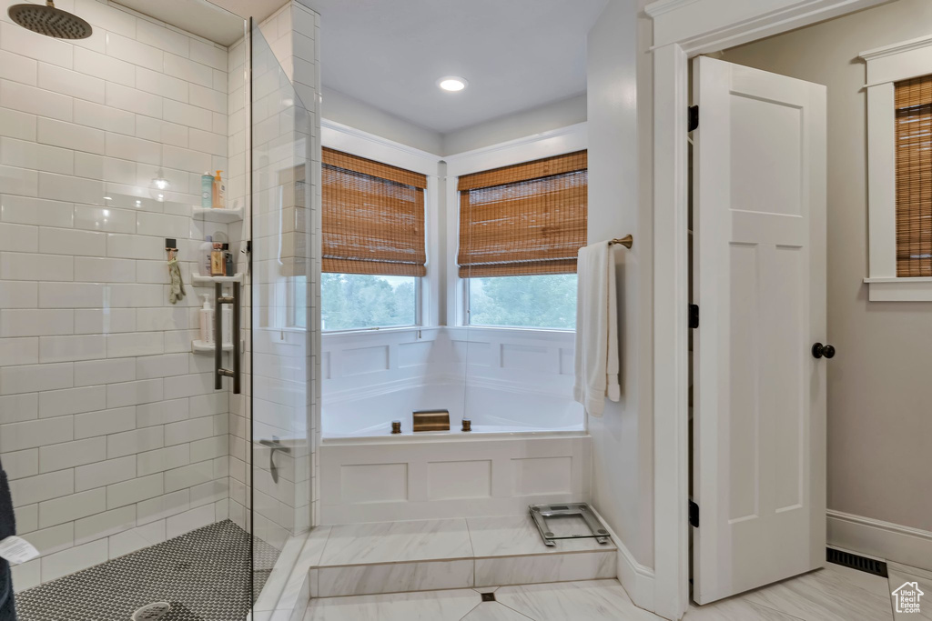 Bathroom featuring a shower stall, a garden tub, baseboards, and recessed lighting