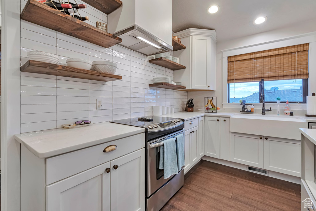 Kitchen with open shelves, electric range, backsplash, recessed lighting, and white cabinetry