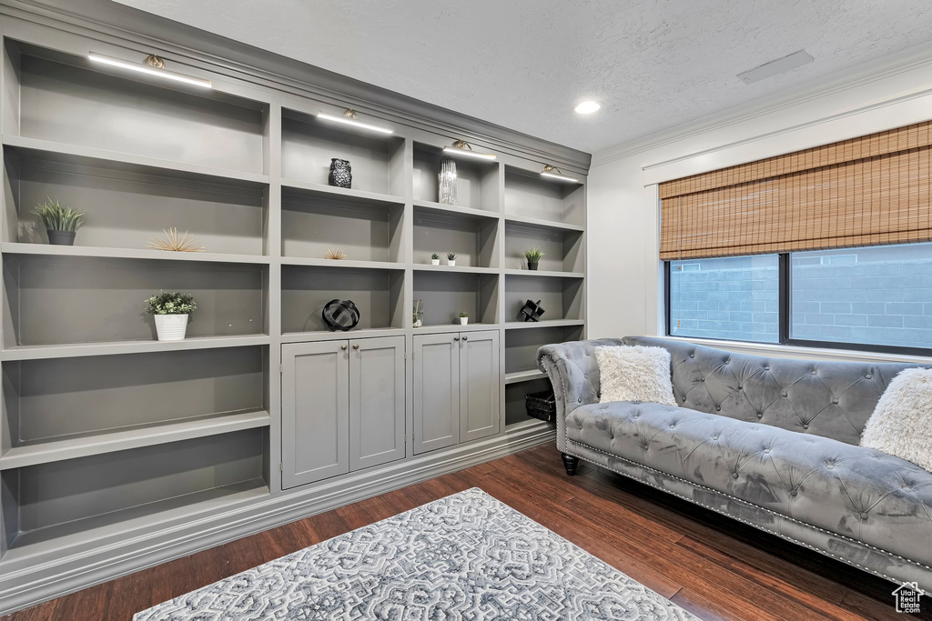 Living area featuring a textured ceiling, dark wood-style flooring, ornamental molding, and recessed lighting
