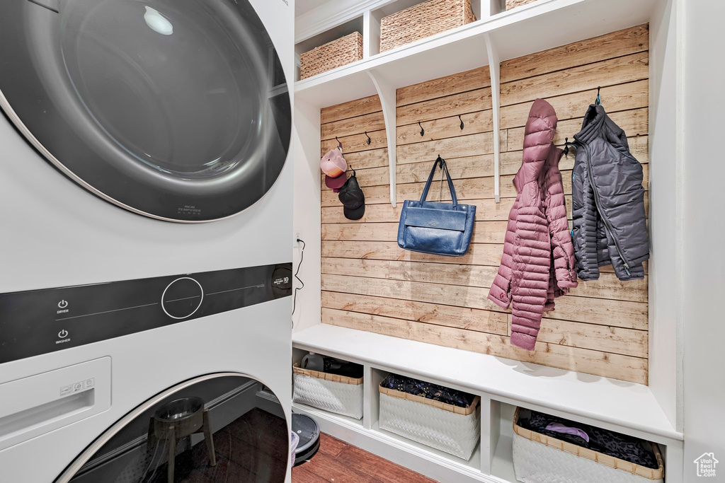 Mudroom featuring estacked washer and dryer, wood walls, and wood finished floors
