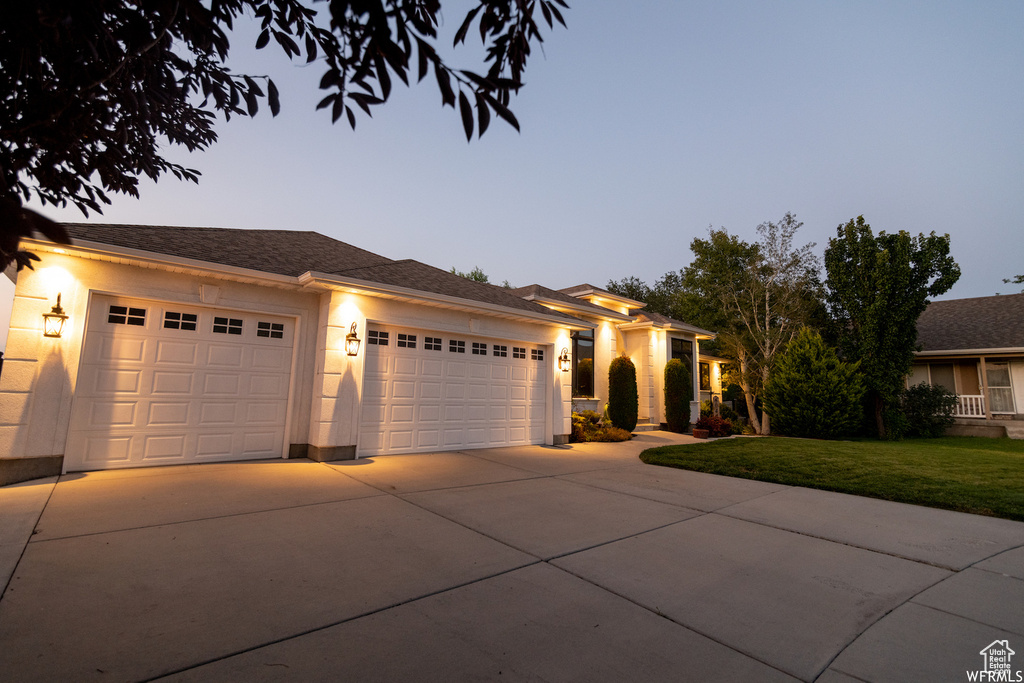 View of front of property with driveway, an attached garage, a front yard, and stucco siding