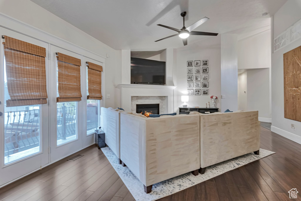 Living room featuring dark wood finished floors, a high end fireplace, ceiling fan, and baseboards