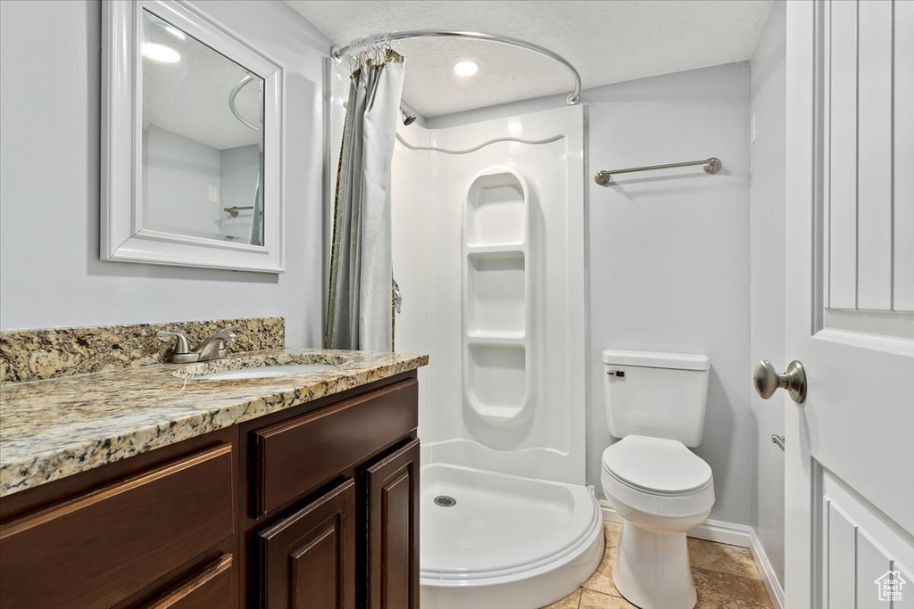 Bathroom with a shower stall, toilet, vanity, and baseboards