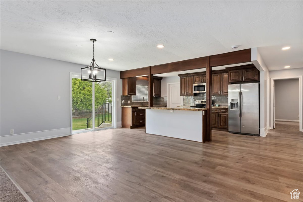 Kitchen featuring appliances with stainless steel finishes, baseboards, dark brown cabinets, backsplash, and recessed lighting
