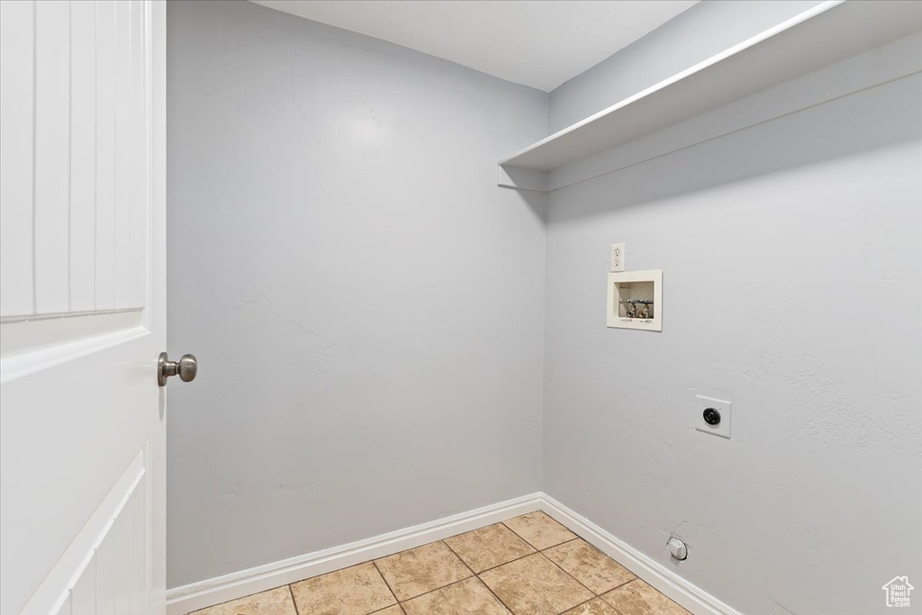 Clothes washing area featuring electric dryer hookup, hookup for a washing machine, baseboards, and light tile patterned floors
