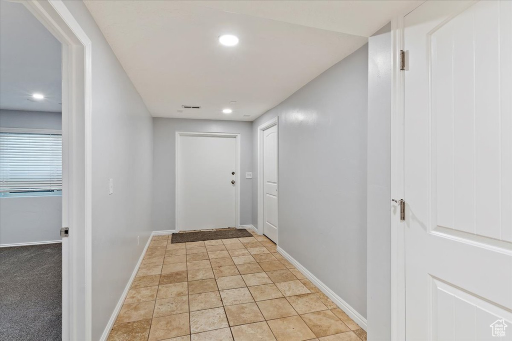 Hall with baseboards, recessed lighting, and light stone finish flooring