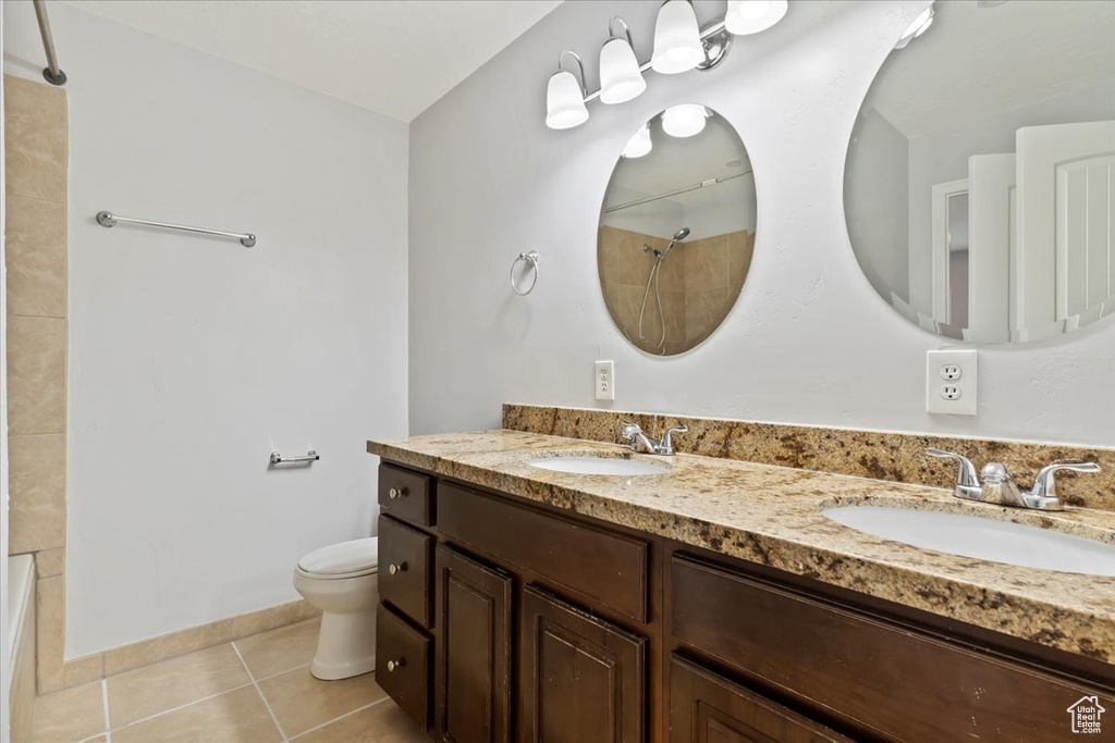 Bathroom featuring toilet, tile patterned flooring, double vanity, and shower / tub combination