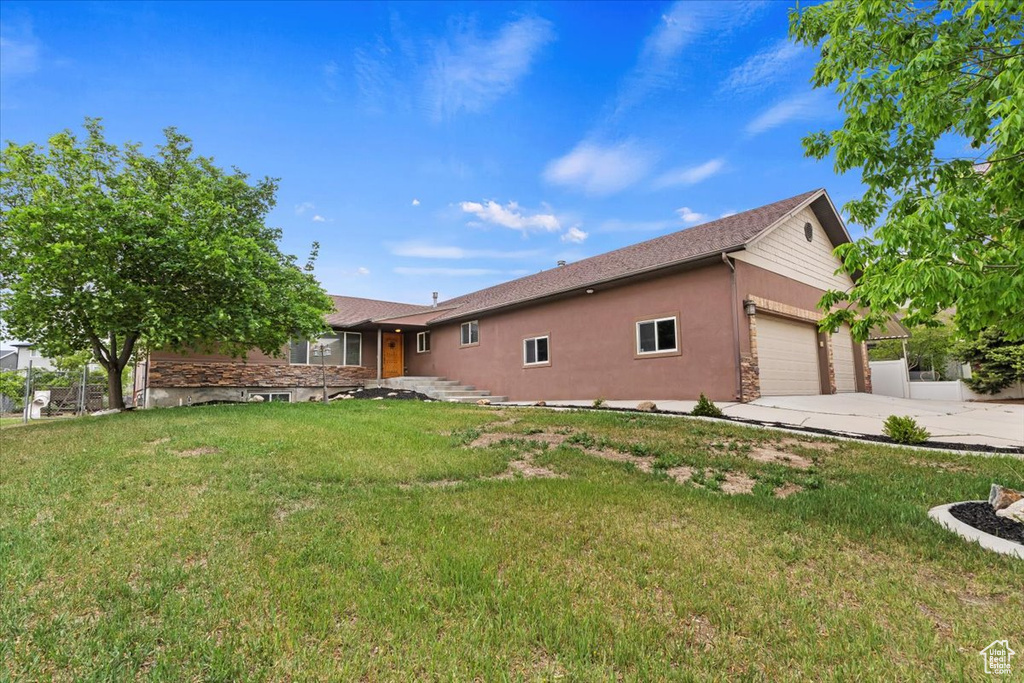 View of side of property featuring a garage, a lawn, concrete driveway, and stucco siding