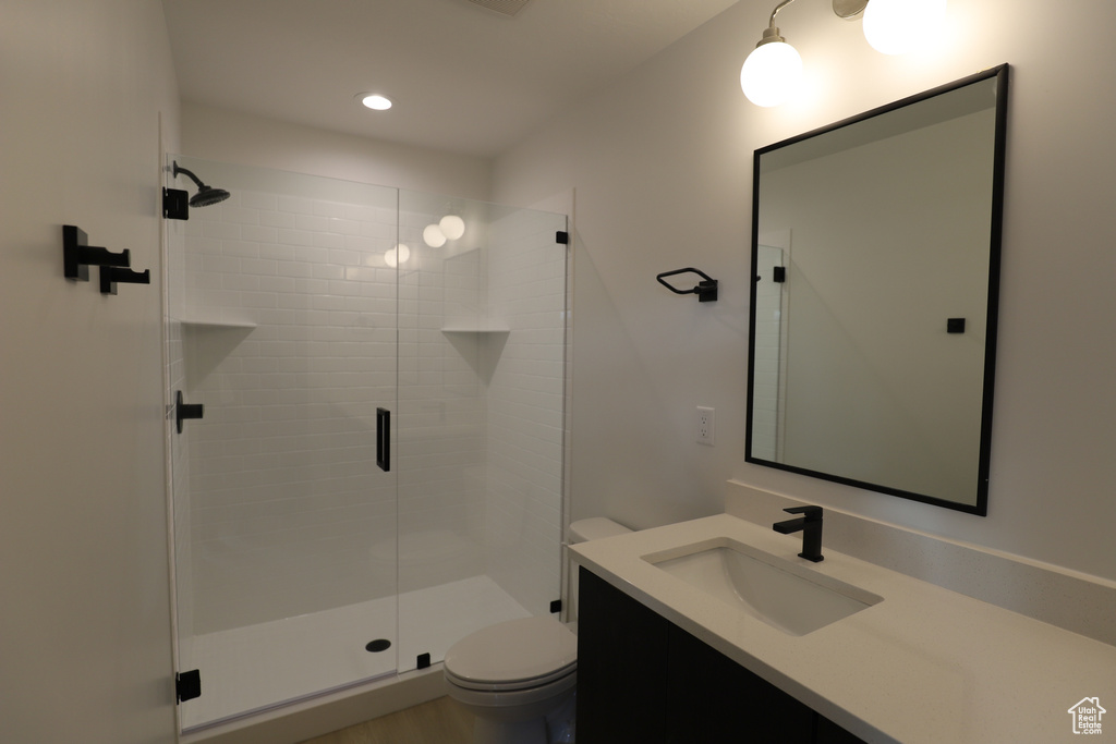 Full bath with toilet, a stall shower, vanity, and recessed lighting