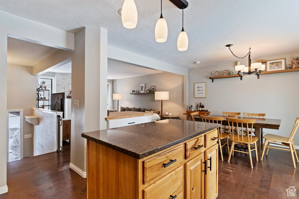 Kitchen featuring dark wood finished floors, a kitchen island, decorative light fixtures, and a chandelier