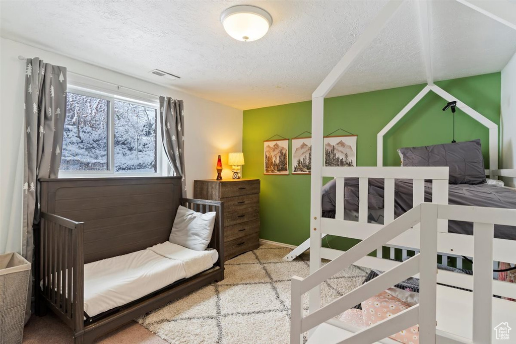 Carpeted bedroom with a textured ceiling and baseboards
