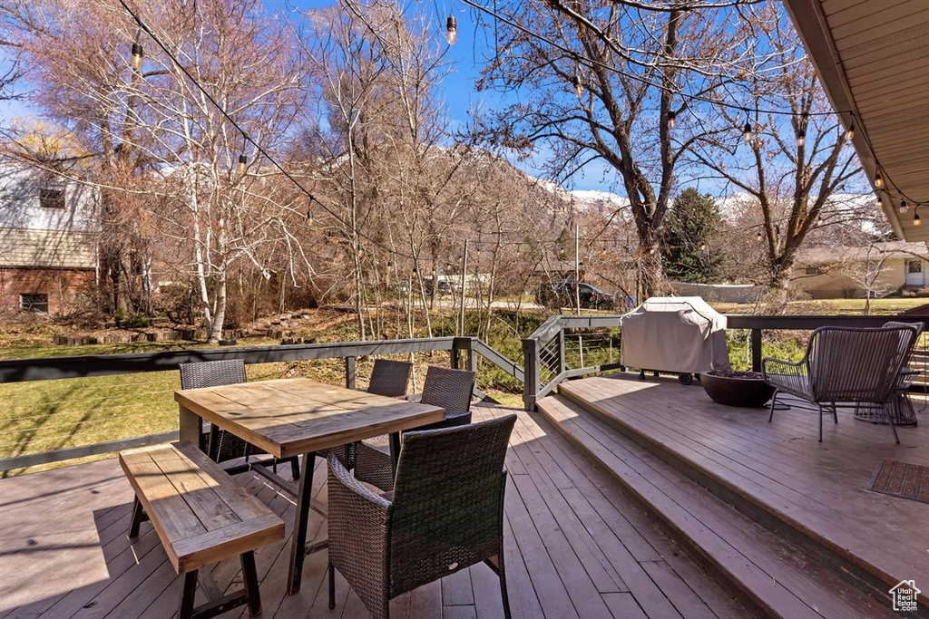 Deck with outdoor dining space, a mountain view, and grilling area