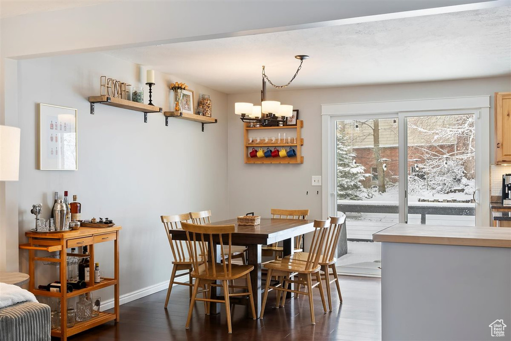 Dining space featuring wood finished floors, a chandelier, and baseboards