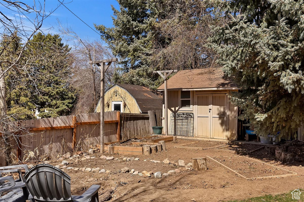 View of yard with fence, a shed, and an outbuilding