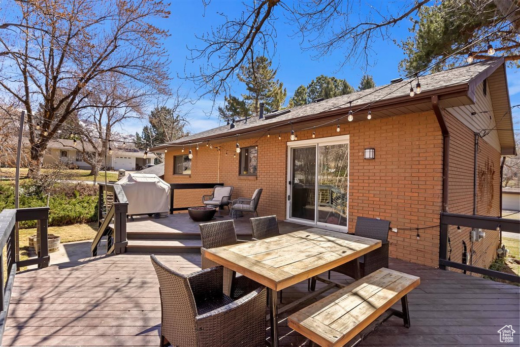 Wooden terrace featuring area for grilling and outdoor dining area