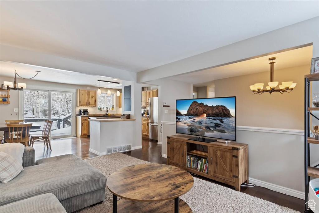Living room featuring a chandelier, dark wood-style flooring, and baseboards