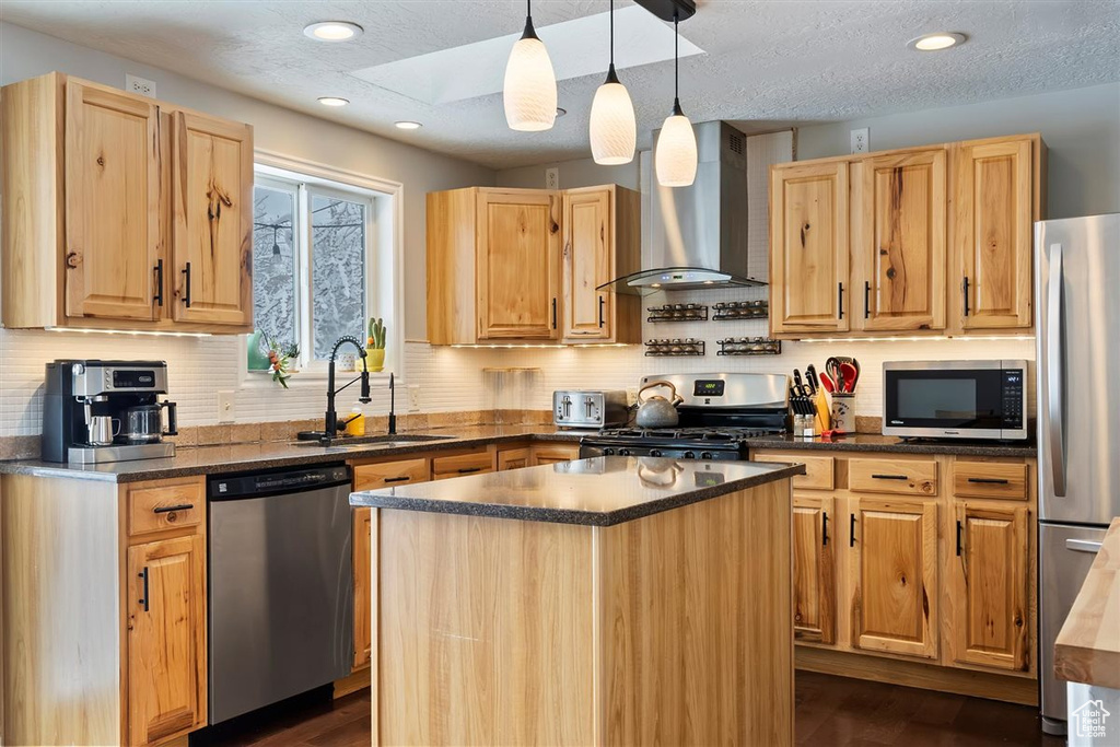 Kitchen featuring stainless steel appliances, wall chimney range hood, a sink, dark wood finished floors, and recessed lighting