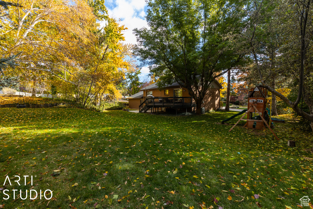 View of green lawn with a deck and a playground