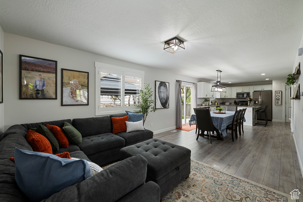 Living area featuring baseboards, light wood-style flooring, recessed lighting, and a textured ceiling