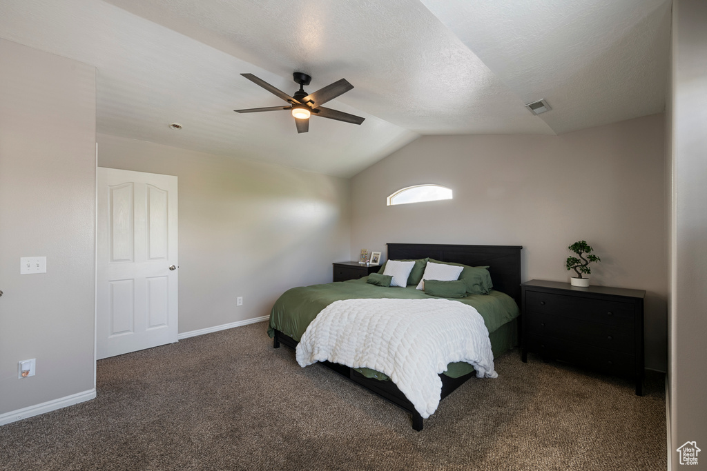 Carpeted bedroom with vaulted ceiling, baseboards, and a ceiling fan