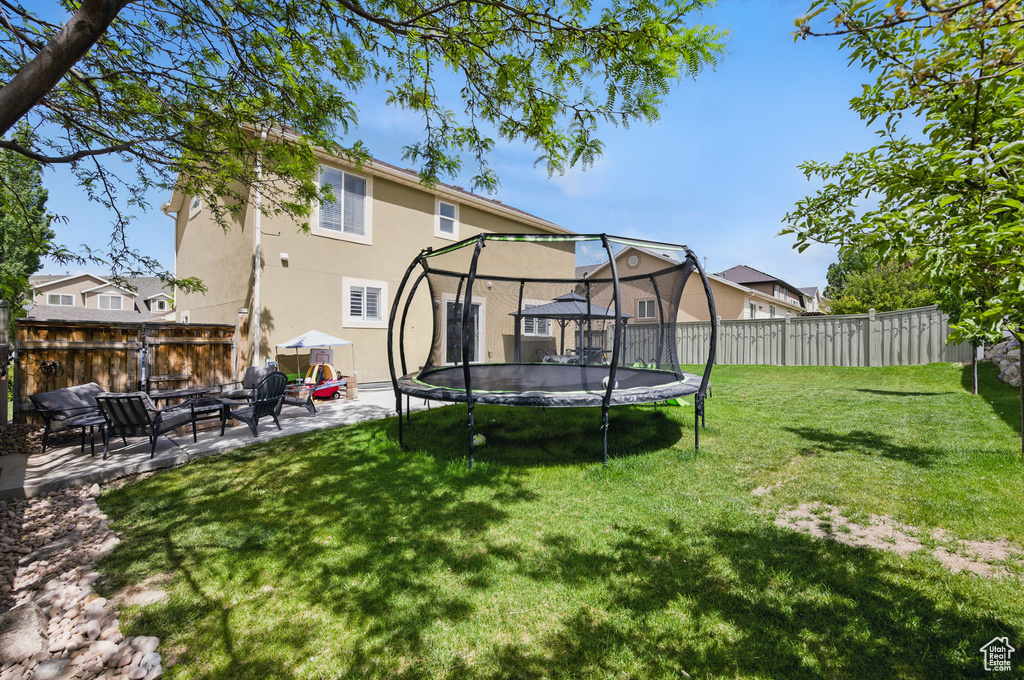 View of yard featuring a trampoline, a patio, and a gazebo