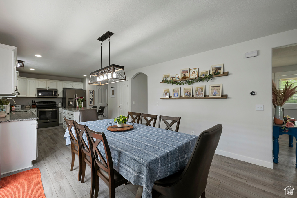 Dining space featuring wood finished floors, arched walkways, recessed lighting, and baseboards