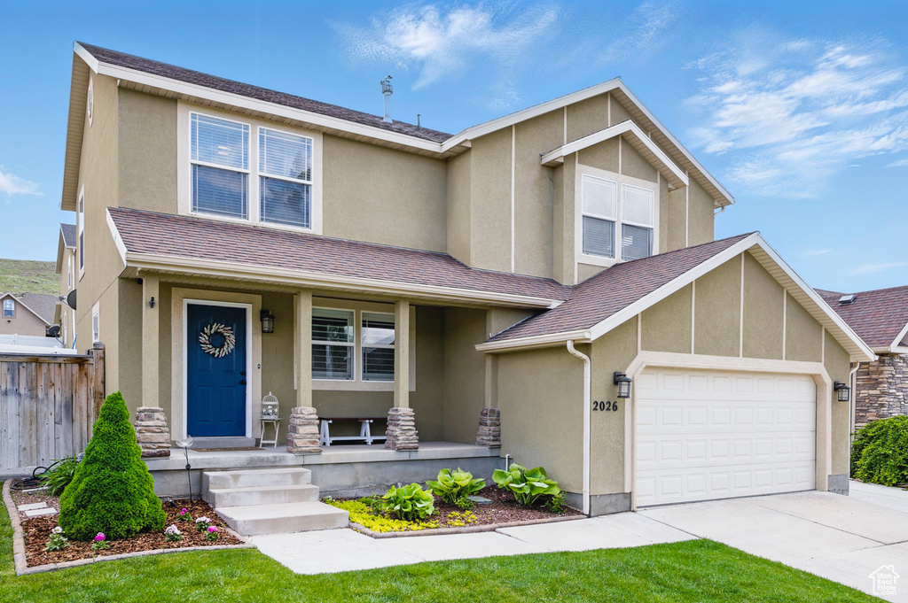 View of front of house with a porch, stucco siding, driveway, a garage, and fence