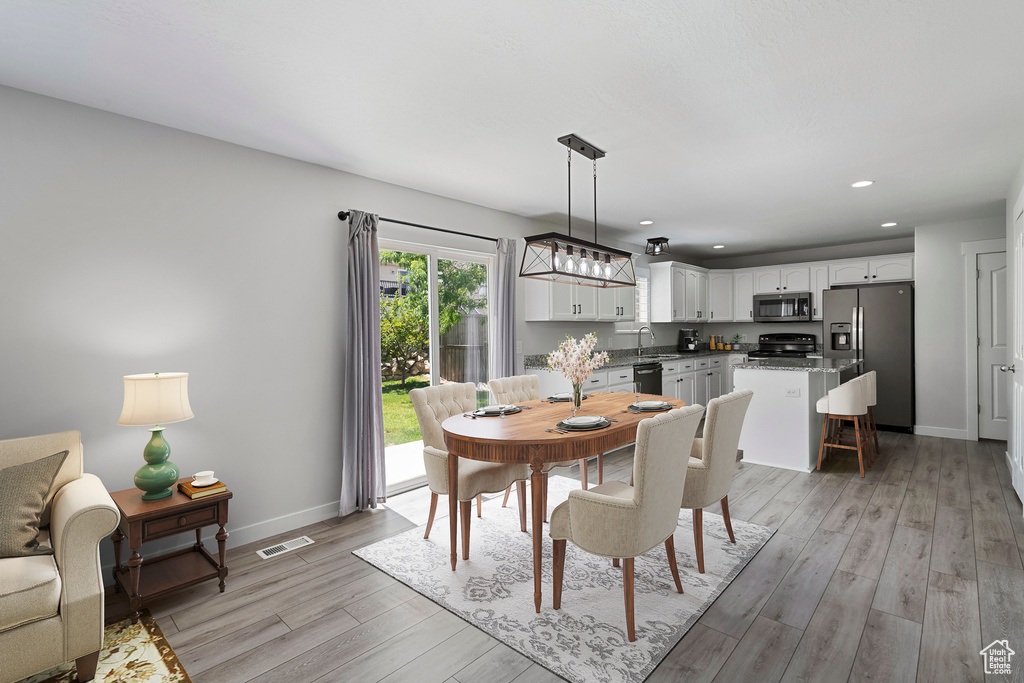 Dining room with light wood-style floors and recessed lighting