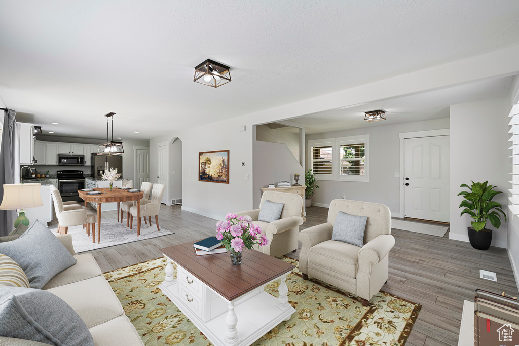 Living area featuring arched walkways, light wood finished floors, and recessed lighting