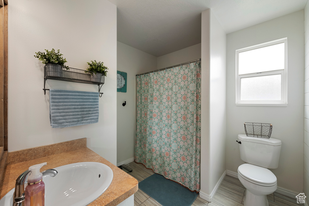 Full bathroom featuring a sink, toilet, curtained shower, and baseboards
