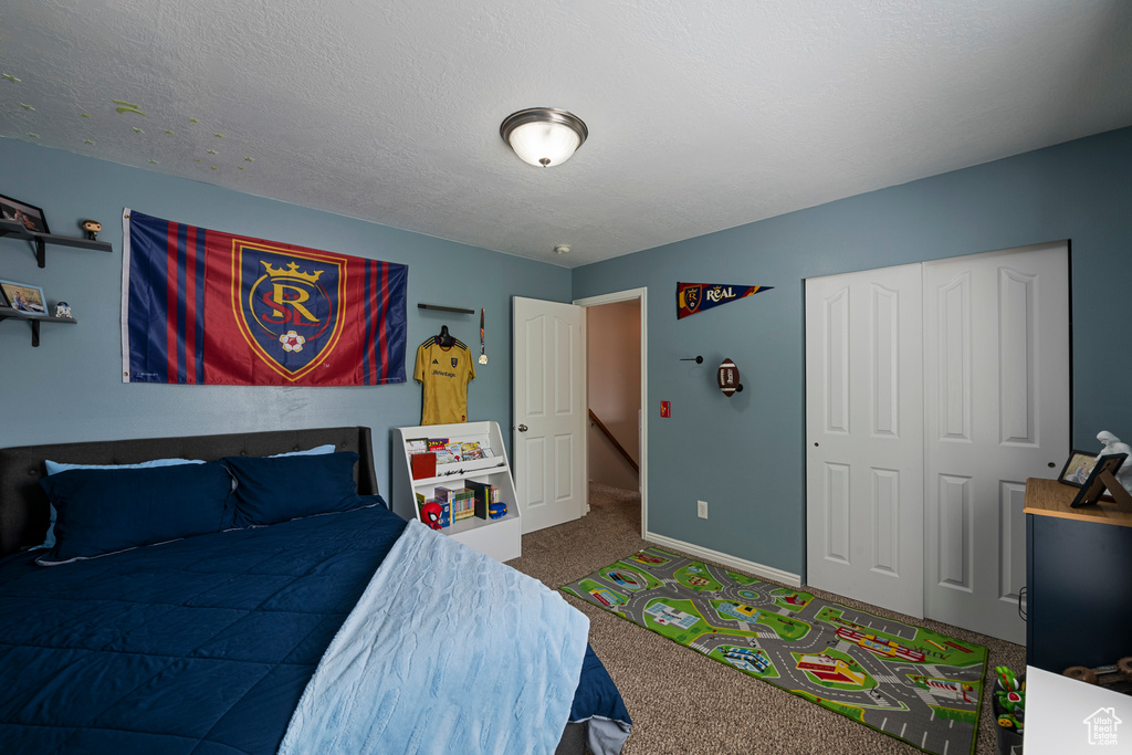 Carpeted bedroom featuring baseboards, a closet, and a textured ceiling