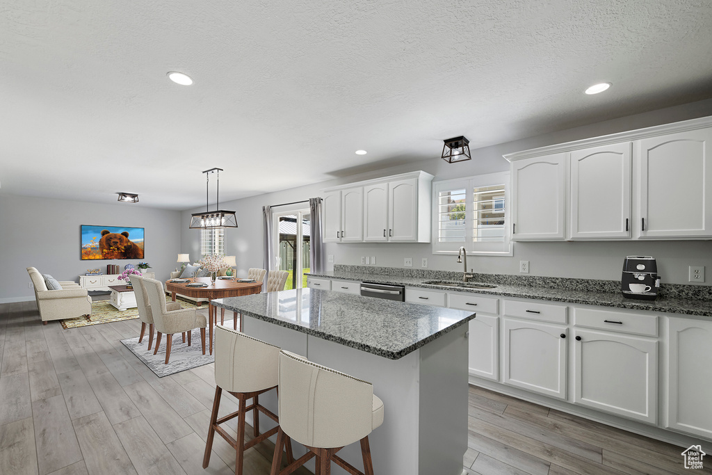 Kitchen featuring stainless steel dishwasher, white cabinets, plenty of natural light, light stone counters, and recessed lighting