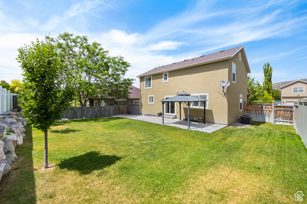 Back of house featuring a gazebo, stucco siding, a patio area, and a fenced backyard