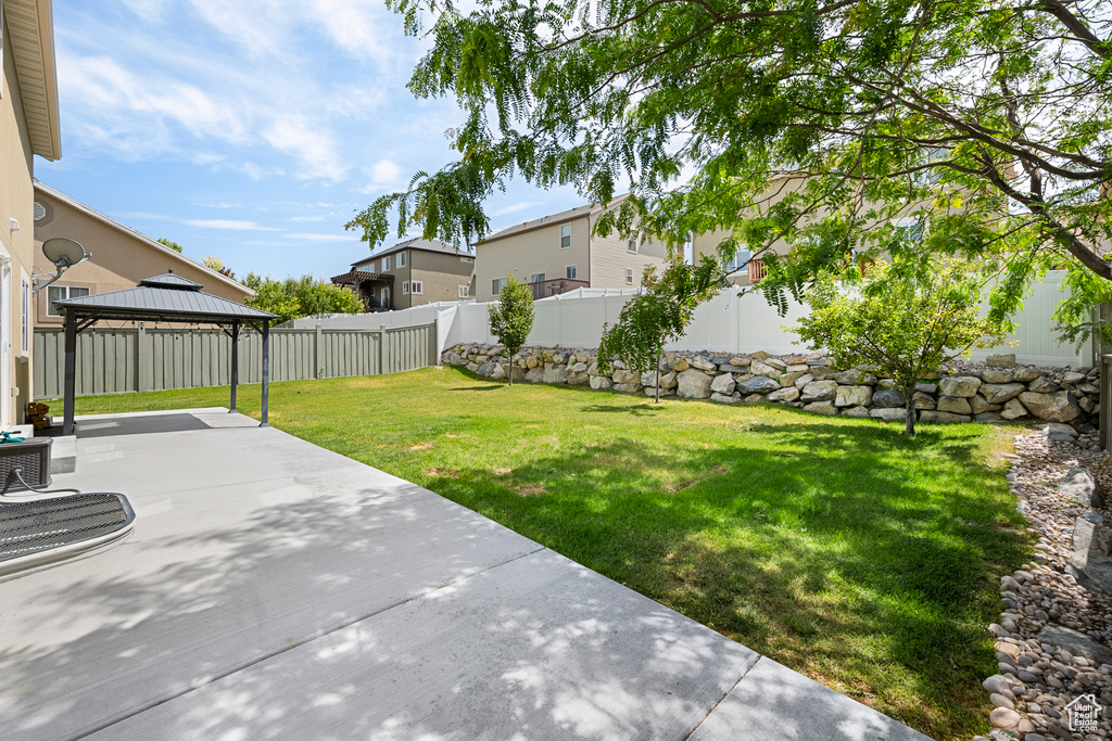 Fenced backyard featuring a patio area and a gazebo