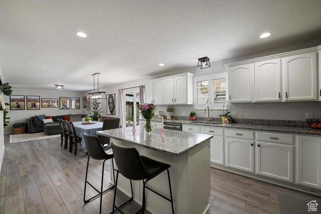 Kitchen with a sink, white cabinets, plenty of natural light, stone countertops, and recessed lighting