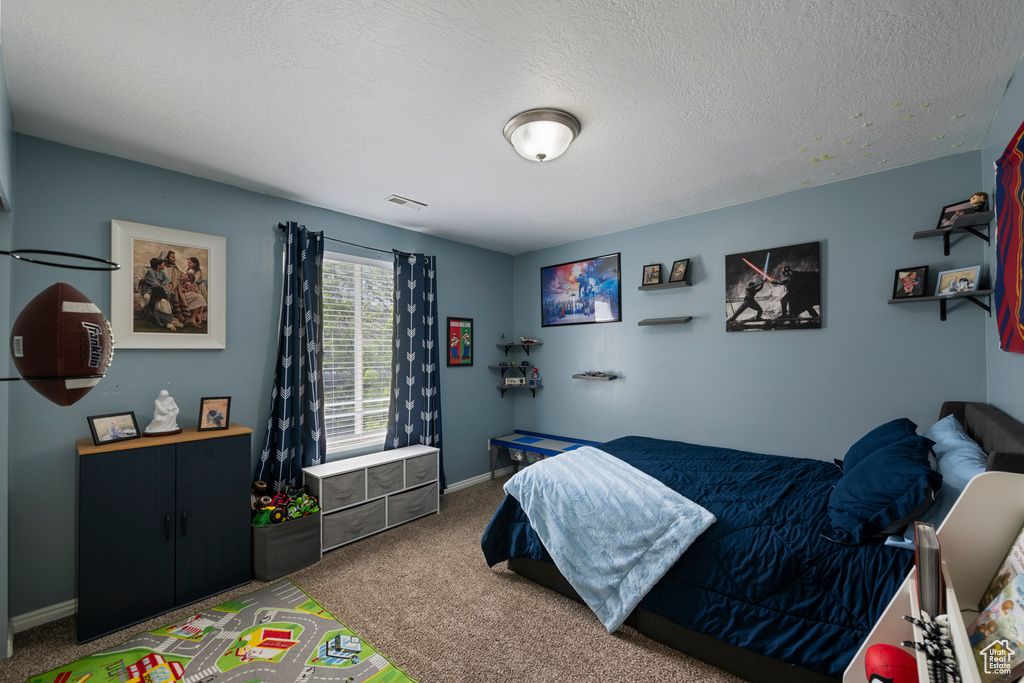 Bedroom with carpet flooring, baseboards, and a textured ceiling