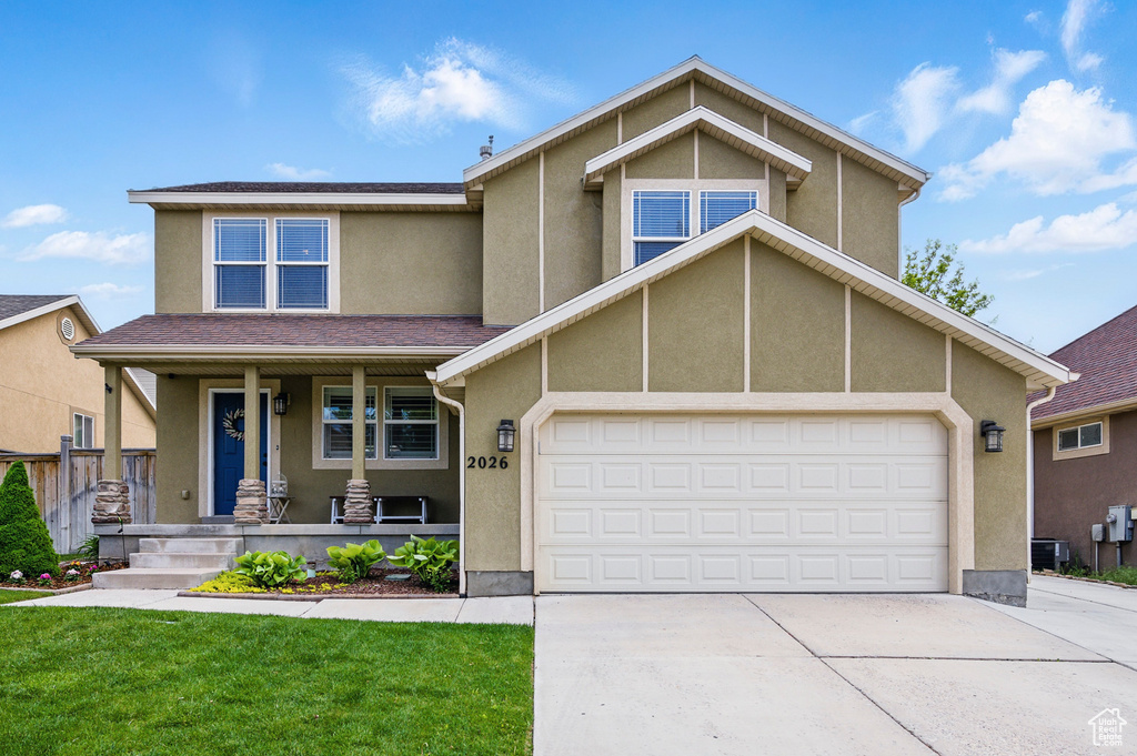 View of front facade featuring driveway, covered porch, an attached garage, stucco siding, and a front lawn