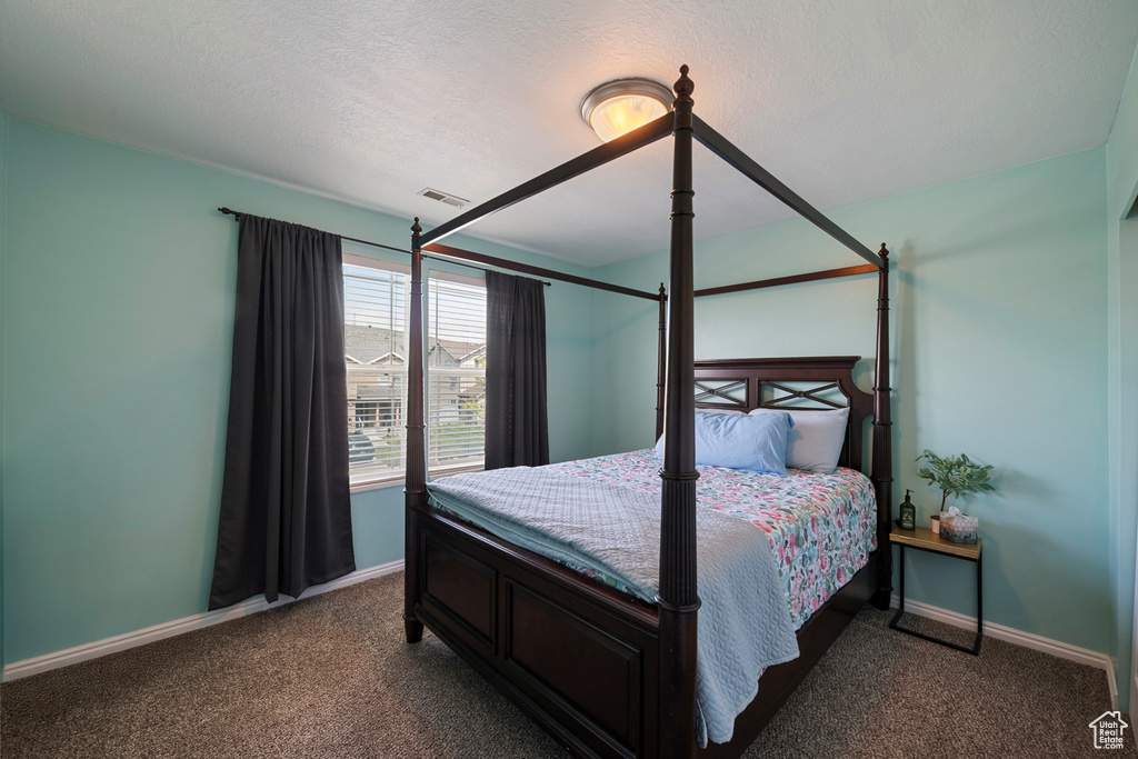 Bedroom featuring dark carpet, baseboards, and a textured ceiling