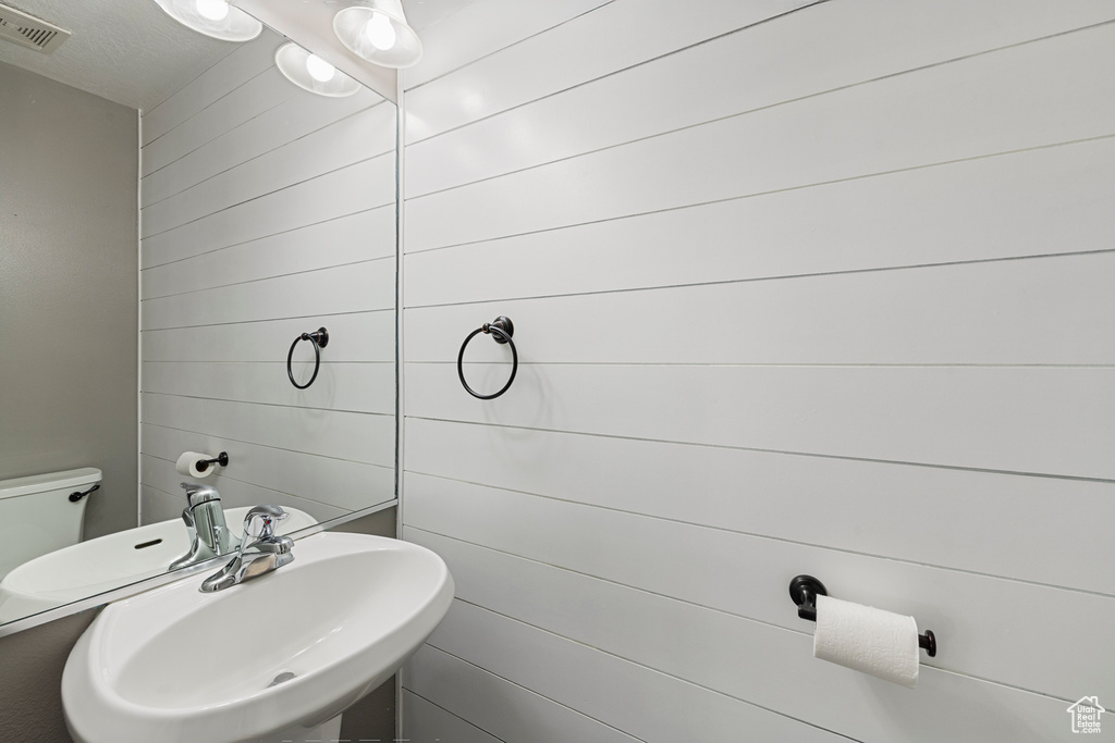 Half bath featuring a sink and wooden walls