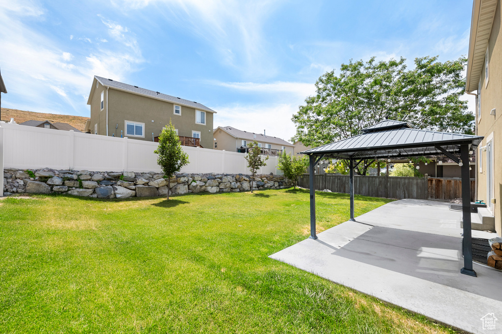Fenced backyard with a gazebo, a patio area, and a residential view